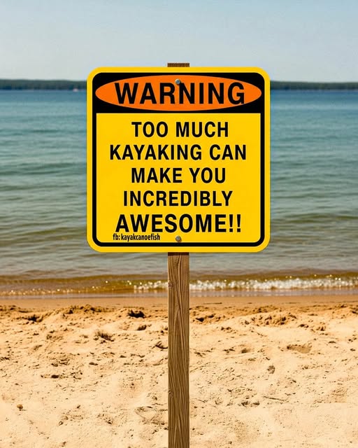 Gele waarschuwingsbord op een strand met de tekst "WARNING: TOO MUCH KAYAKING CAN MAKE YOU INCREDIBLY AWESOME!!" 